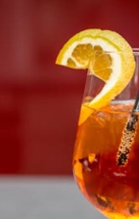 A glass of orange drink garnished with a lemon wedge, featured in the Angostura Bitters Recipe guide.