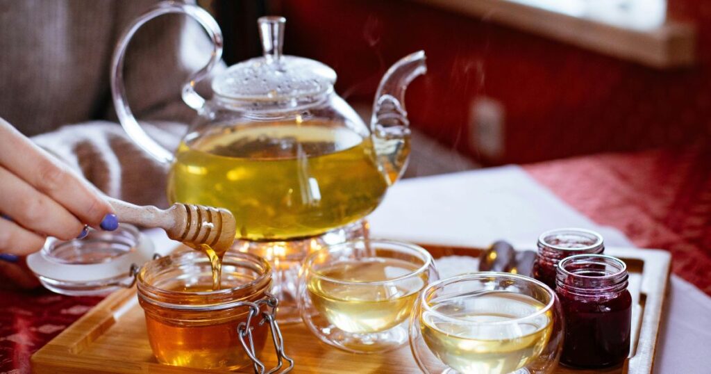 A collection of ingredients for homemade iced tea, including tea bags, fresh lemons, and mint leaves on a wooden table.