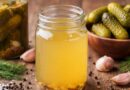 Jars of pickles and pickling ingredients arranged on a wooden table, illustrating a guide on making pickle juice for cramps.