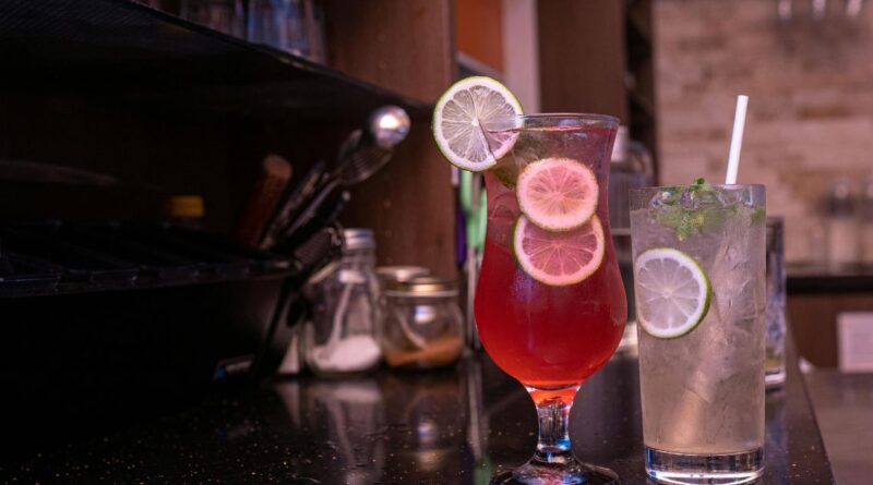 A bar counter displays two drinks, featuring a refreshing Jack Honey Lemonade.