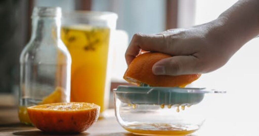  How to Make Orange Juice Without a Juicer,
Close-up of a person pressing an orange into a glass, illustrating the process of making orange juice without a juicer.
