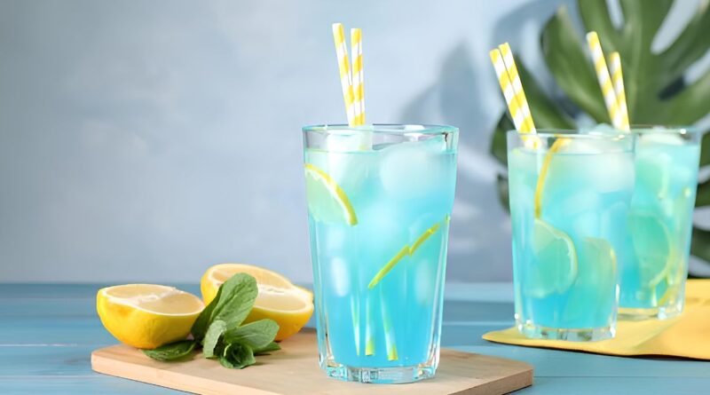 Glass of blue lemonade with straws and lemon slices, illustrating a sweet and refreshing drink recipe.